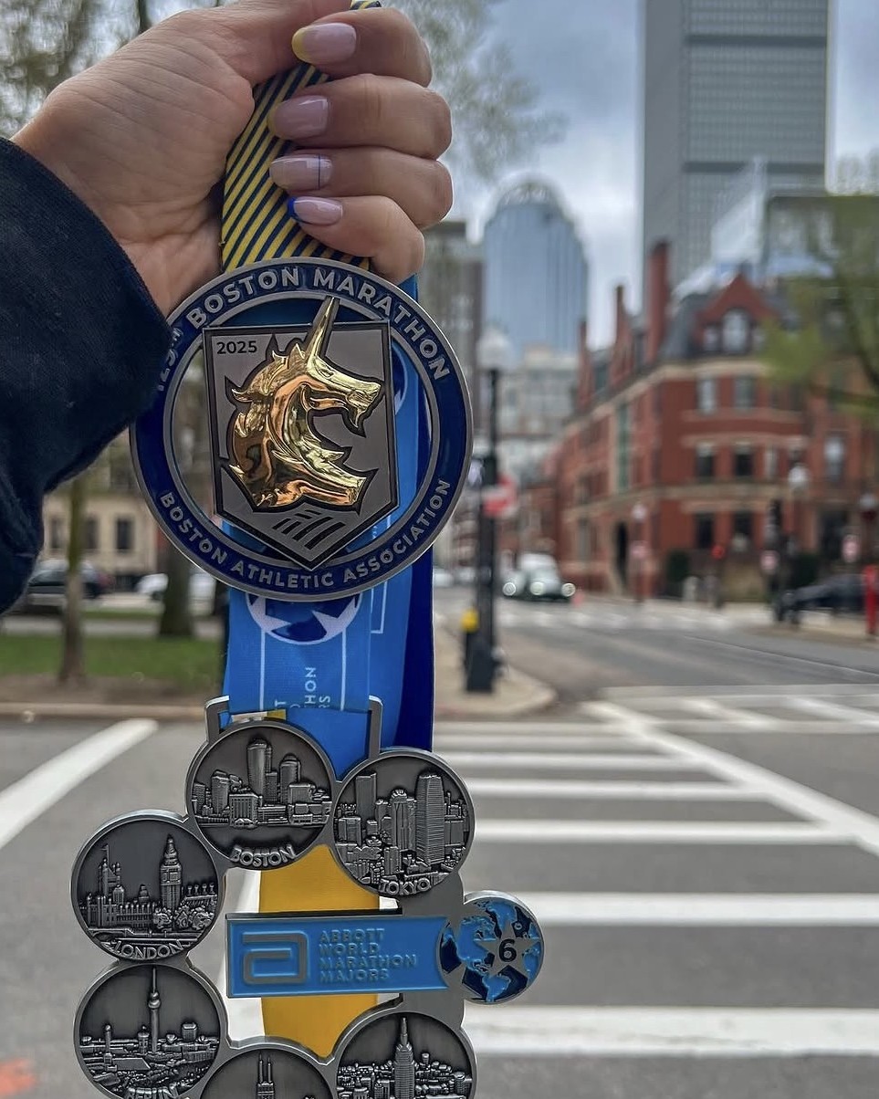 Sam's six World Marathon Majors medals held up on a Boston street